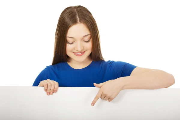 Gelukkig woman wijzend op leeg bord. — Stockfoto