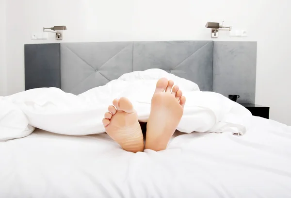 Blote dames voeten in slaapkamer. — Stockfoto