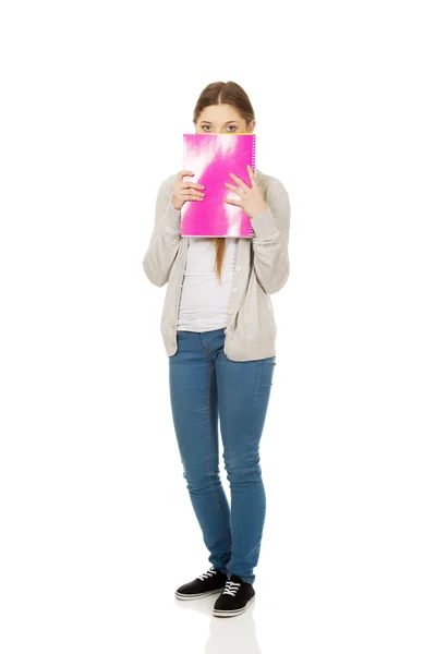 Mulher adolescente escondida atrás de um caderno . — Fotografia de Stock