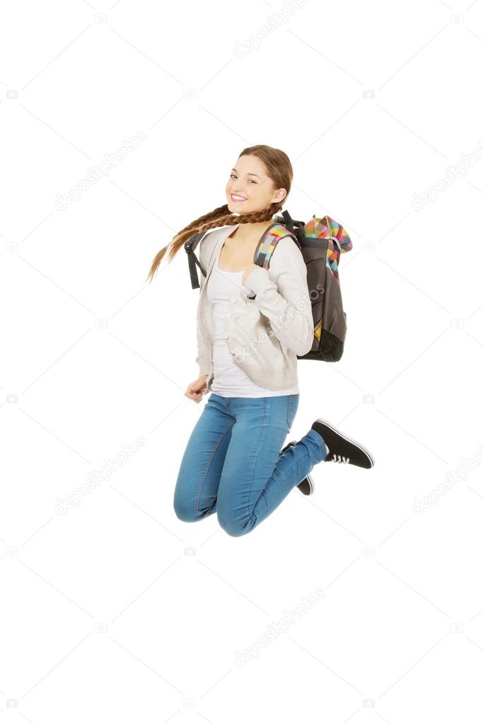 Teen woman jumping with backpack.