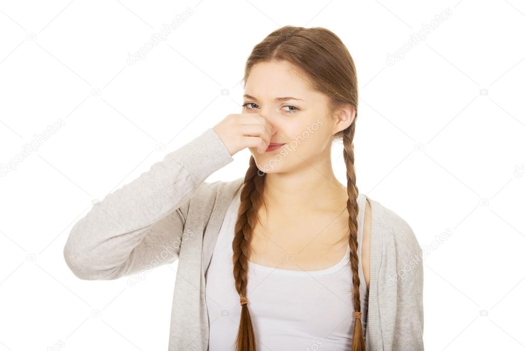 Disgusted teen woman pinching nose.
