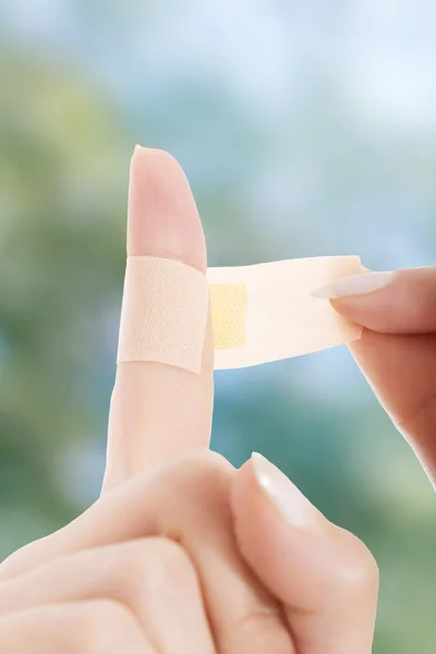 Mujer poniendo cinta adhesiva en el dedo . — Foto de Stock