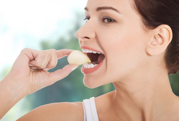 Mooie vrouw eten knoflook. — Stockfoto