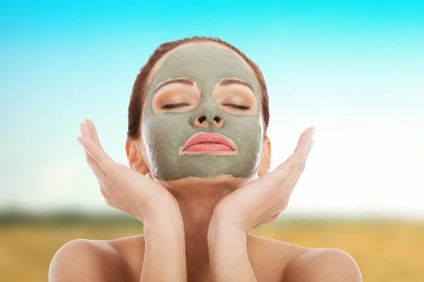 Beautiful woman with clay facial mask. — Stock Photo, Image