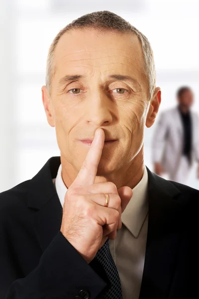 Reifer Mann mit Finger auf den Lippen. — Stockfoto