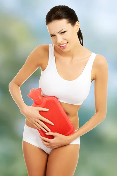 Woman with stomachache and hot water bottle. — Stock Photo, Image