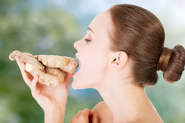 Beautiful woman eating fresh ginger. — Stock Photo, Image