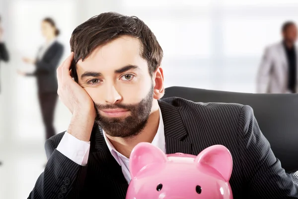 Businessman with piggybank by a desk. — Stock Photo, Image