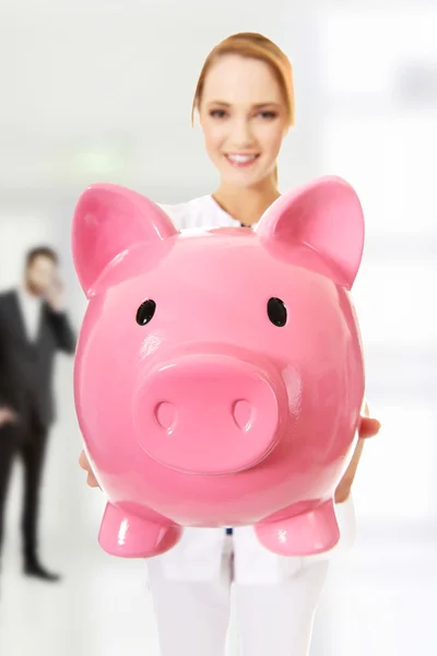 Doctor holding a piggybank. — Stock Photo, Image