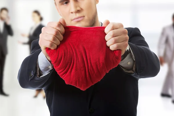 Homme d'affaires déchire oreiller en forme de coeur . — Photo