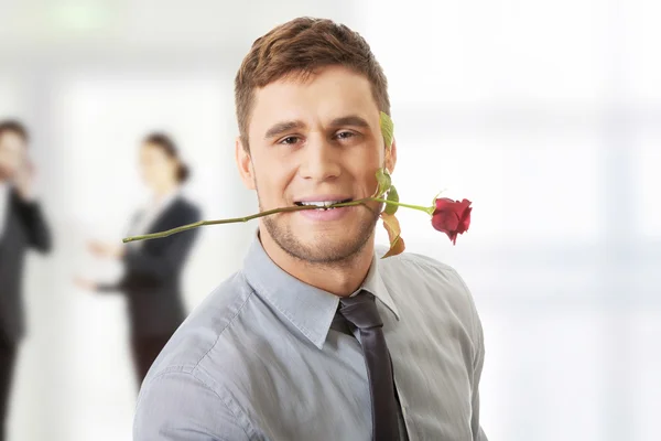 Pohledný muž, který držel červené růže v ústech. — Stock fotografie