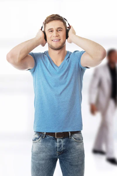 Hombre guapo escuchando música con auriculares. — Foto de Stock