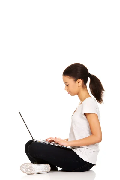 Teen sedí se zkříženýma nohama s notebookem. — Stock fotografie