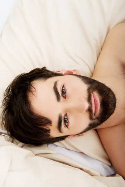 Young muscular man lying in bed. — Stock Photo, Image