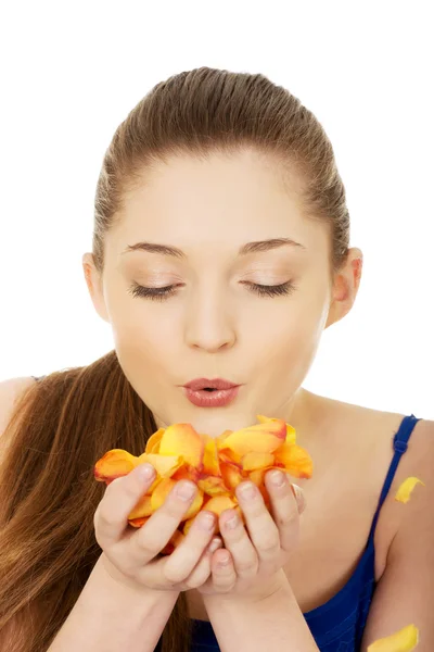 Genç kadın gül yaprakları üfleme. — Stok fotoğraf
