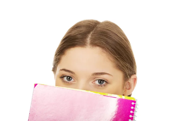 Mulher adolescente escondida atrás de um caderno . — Fotografia de Stock