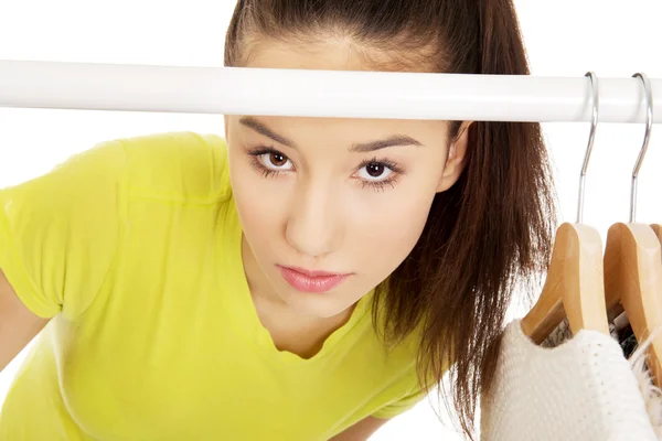 Young woman with clothes on hanger. — Stock Photo, Image