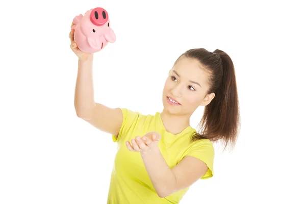 Glückliche Frau schüttelt Sparschwein. — Stockfoto