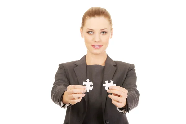 Businesswoman holding two puzzles. — Stock Photo, Image