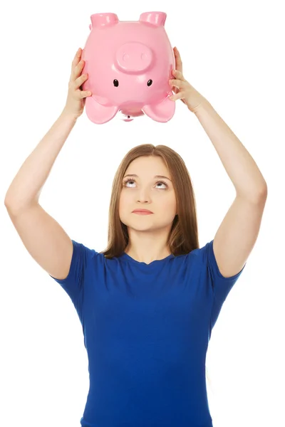 Teenager-Frau schüttelt Sparschwein. — Stockfoto