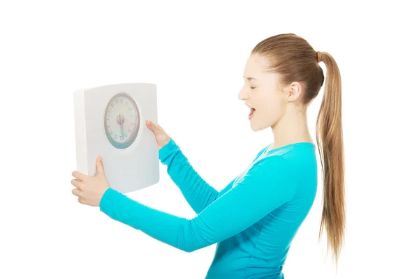 Young unhappy woman with scale. — Stock Photo, Image