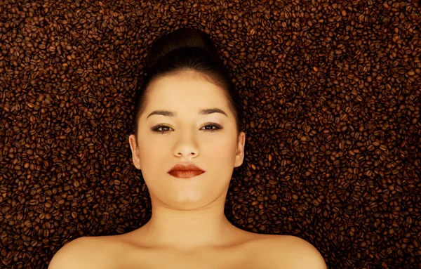 Attractive woman lying in coffee grains. — Stock Photo, Image