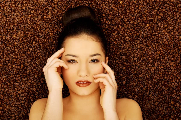 Mujer atractiva acostada en granos de café . — Foto de Stock
