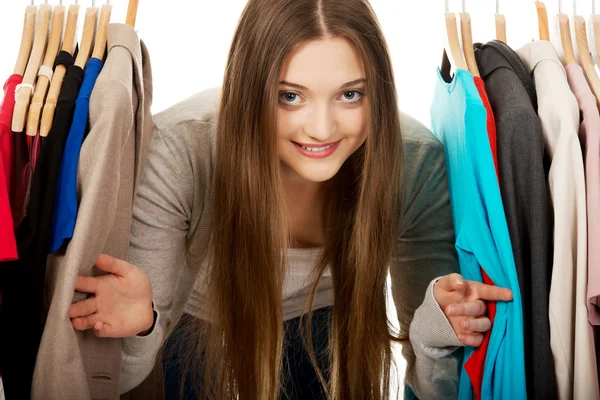 Teen Frau zwischen Kleidern auf Kleiderbügel. — Stockfoto