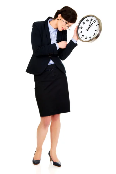 Müde Geschäftsfrau hält Uhr in Händen. — Stockfoto