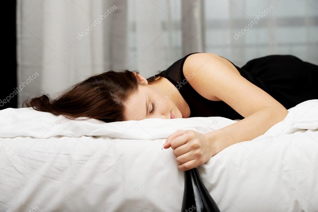 Drunk young woman sleeping on bed.
