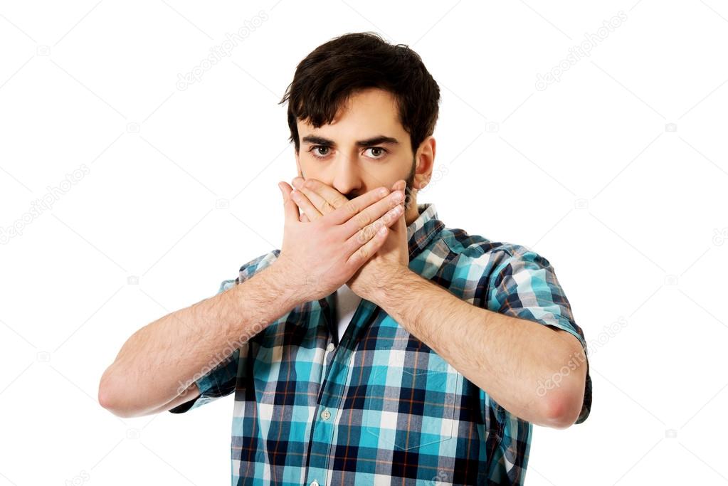 Young shocked man covering his mouth.