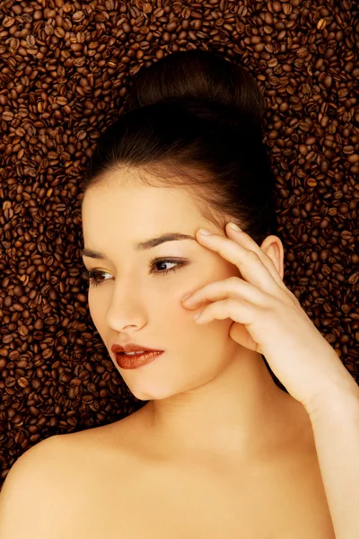 Attractive woman lying in coffee grains. — Stock Photo, Image