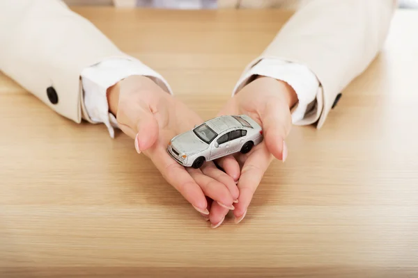 Mulher de negócios segurando um carro de brinquedo . — Fotografia de Stock