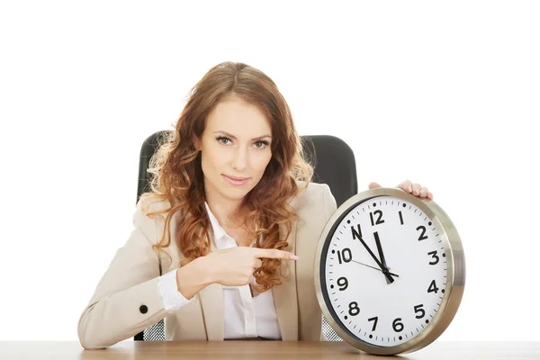 Zakenvrouw wijzen op een klok door een helpdesk. — Stockfoto