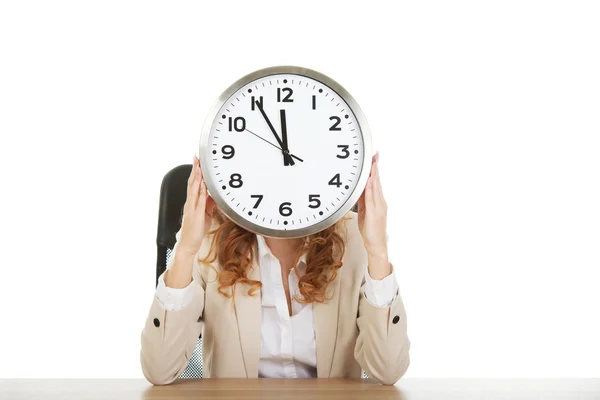 Businesswoman with clock by a desk. Stock Image