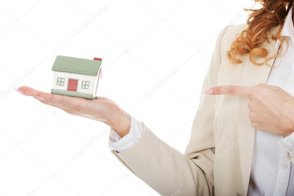 Businesswoman pointing on a model house.