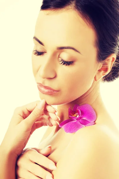 Naken kvinna med lila orkidé kronblad på axel — Stockfoto