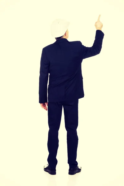 Affärsman med hjälm pekar uppåt — Stockfoto