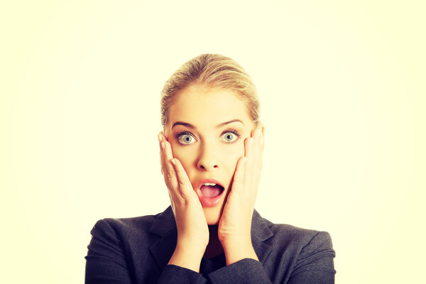 Шокированная женщина держит руки на подбородке
