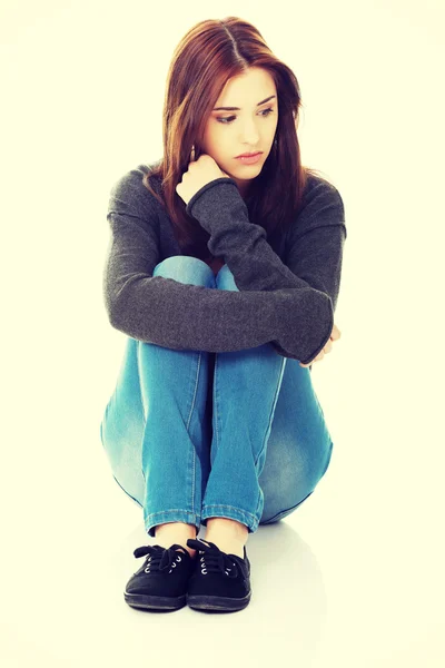 Casual young woman sitting on white floor — Stock Photo, Image