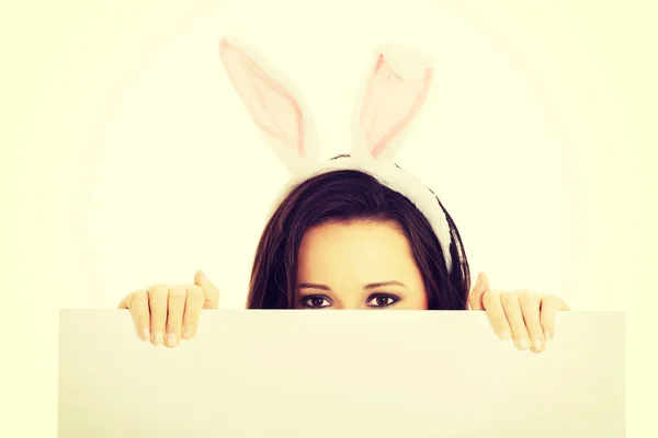 Vrouw dragen bunny oren en houden een leeg baner — Stockfoto