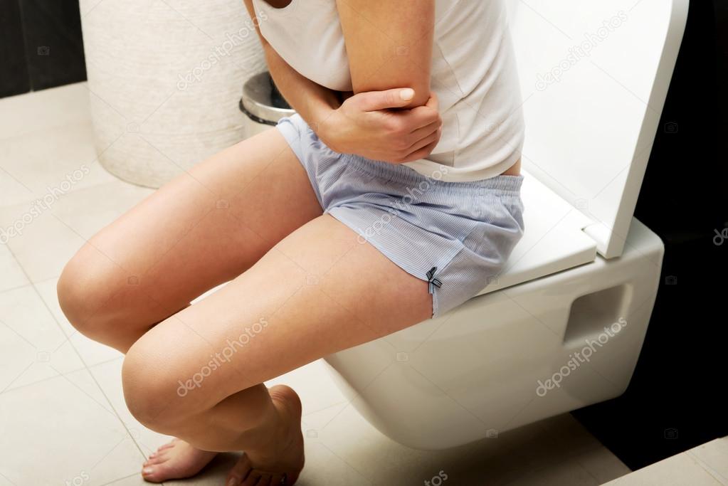 Woman is sitting on the toilet.