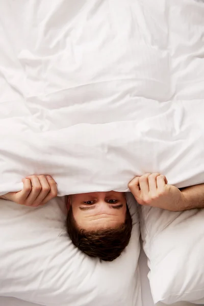 Homem escondido na cama debaixo dos lençóis . — Fotografia de Stock