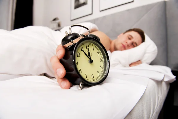 Man with alarm clock in bedroom. — Stock Photo, Image