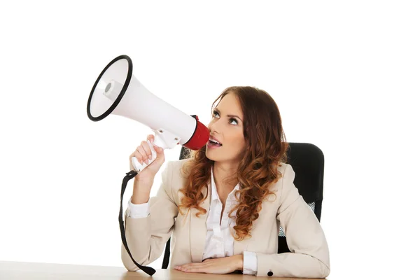 Businesswoman with megaphone by a desk. — Stock Photo, Image