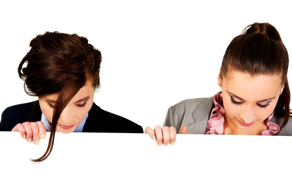 Duas mulheres de negócios carregando uma grande placa branca . — Fotografia de Stock