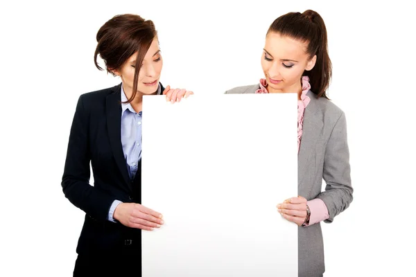 Dos empresarias llevando una gran pizarra blanca . — Foto de Stock