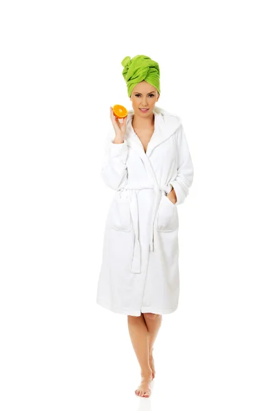 Spa woman in bathrobe holding orange. — Stock Photo, Image