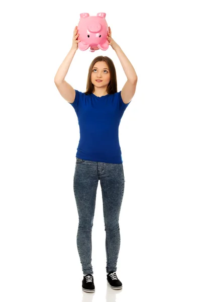 Teenage woman shaking piggybank. — Stock Photo, Image