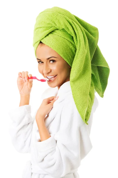 Woman in bathrobe brushing teeth — Stock Photo, Image